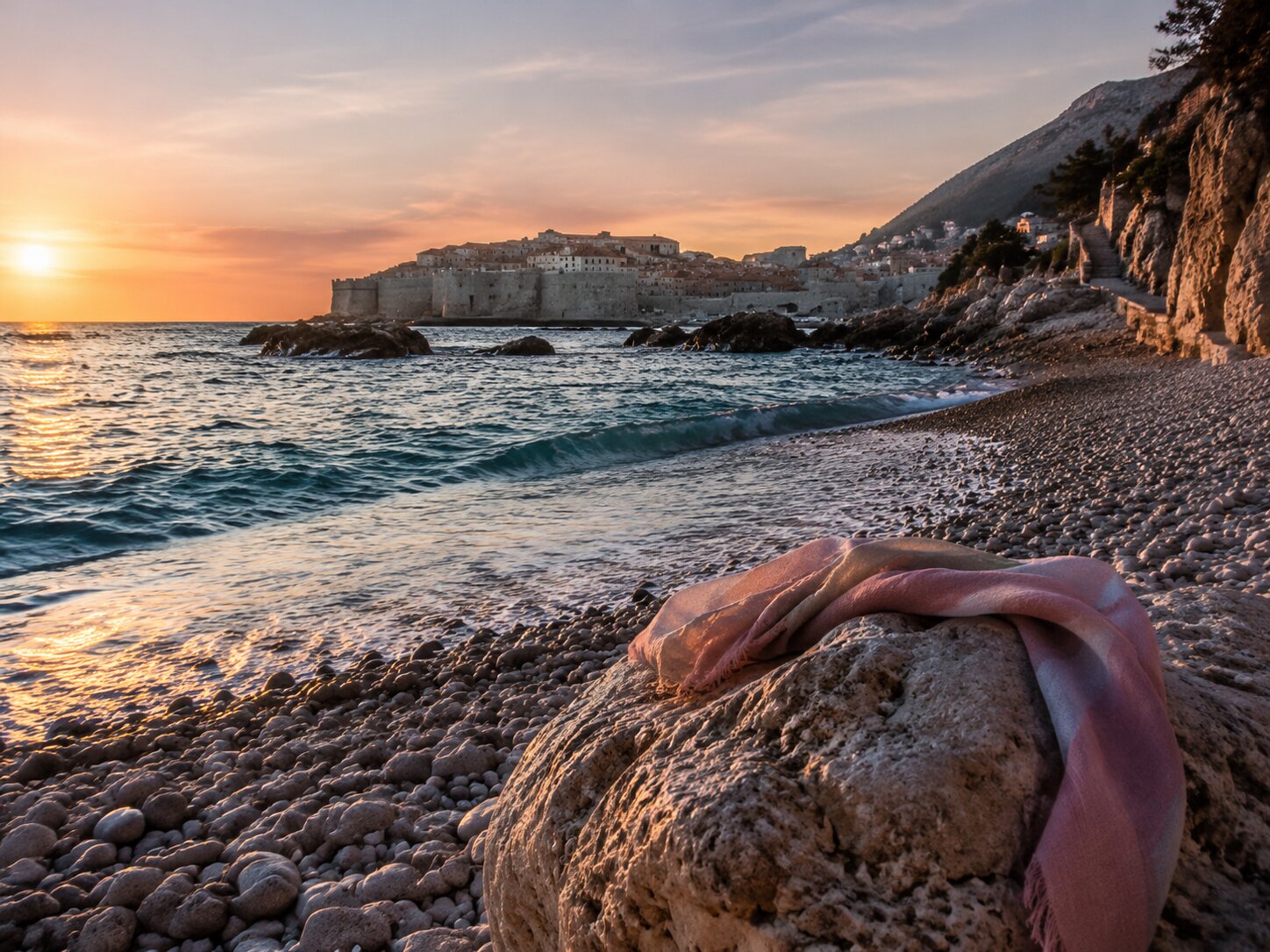 A shawl left on a stone, a town waiting across the water